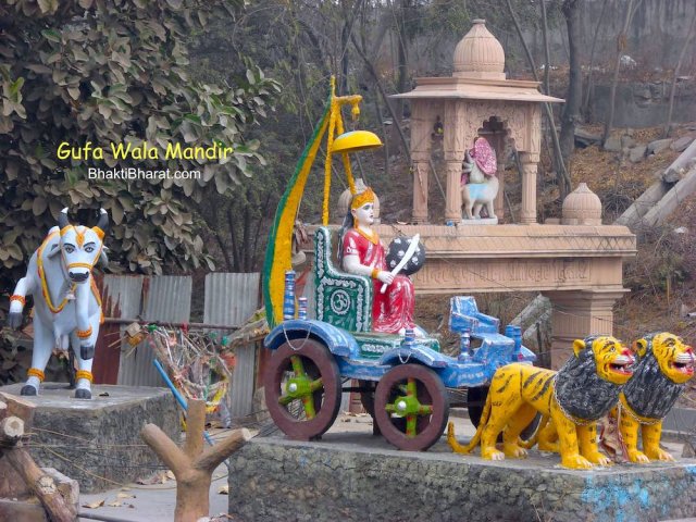 A symbolic representation of Bharat Maa riding on Rath having two lions. Also side view of Sherawali Maa gate from road side. With pure white bull shows the prosperity of country.